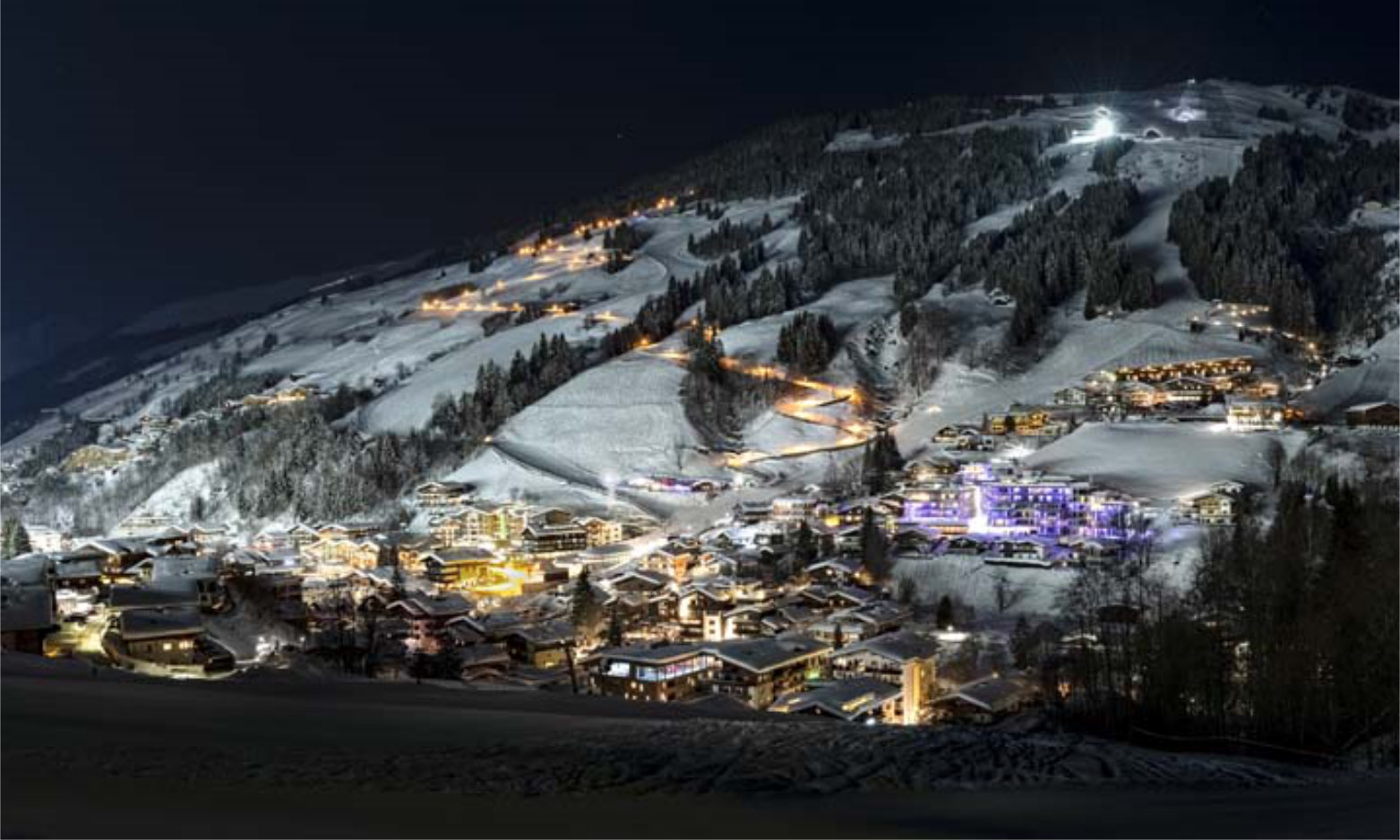 Saalbach-Hinterglemm mit Skipiste bei Nacht mit Flutlicht Panora
